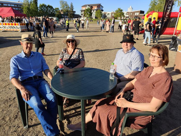 Janne Lehtimäki löysi suositun Lauttarokki-hatun päänsä suojaksi aurinkoisessa illassa. Myös Sanna Lehtimäki sekä Ella ja Harri Kivipelto olivat nauttimassa Lauttarokin tarjonnasta. Kuva: Joonas Sillanpää